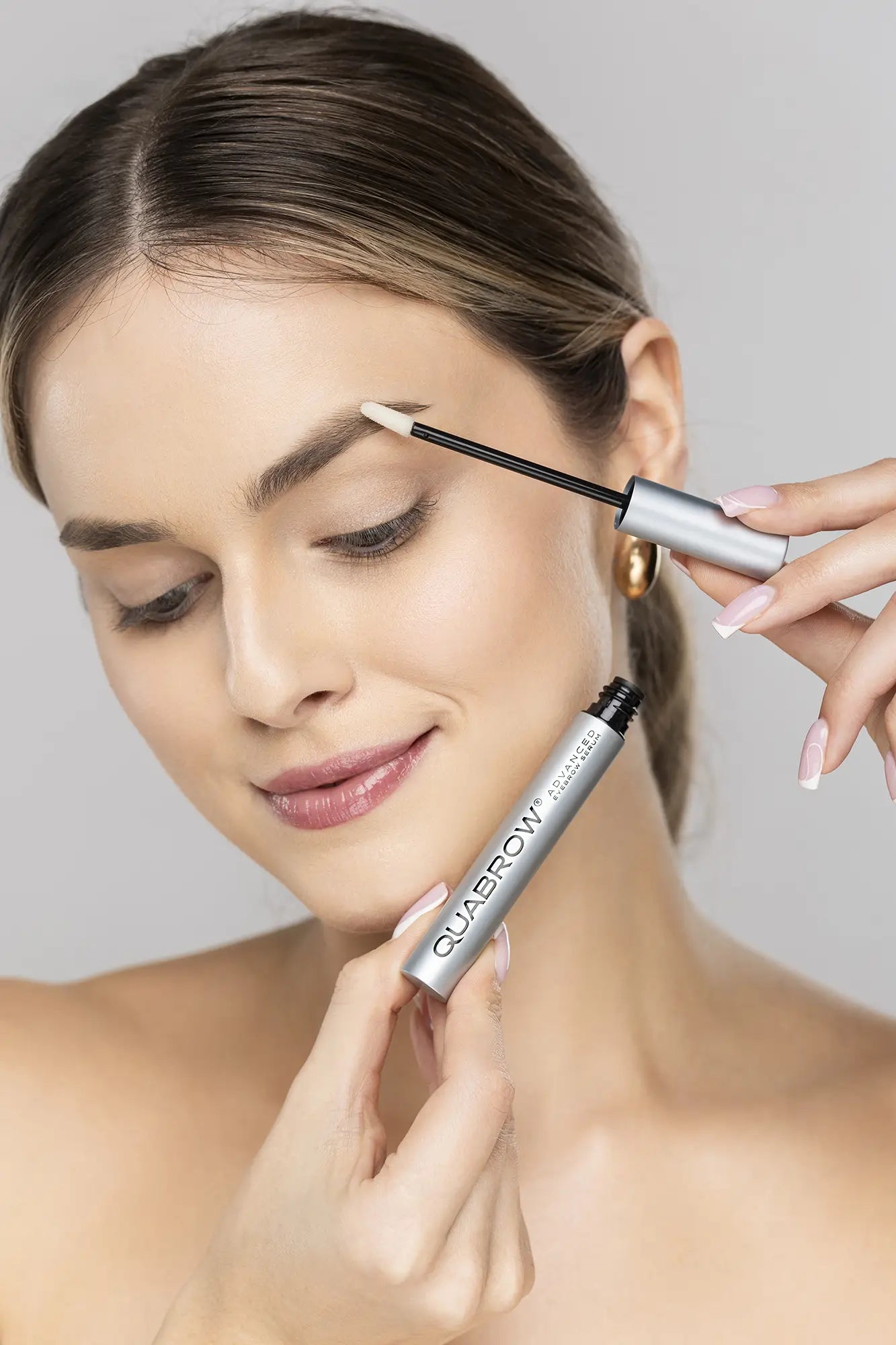 Blonde 여성이 어플리케이터로 QUABROW Advanced Eyebrow Serum을 눈썹에 바르는 모습 – 단계별 사용법