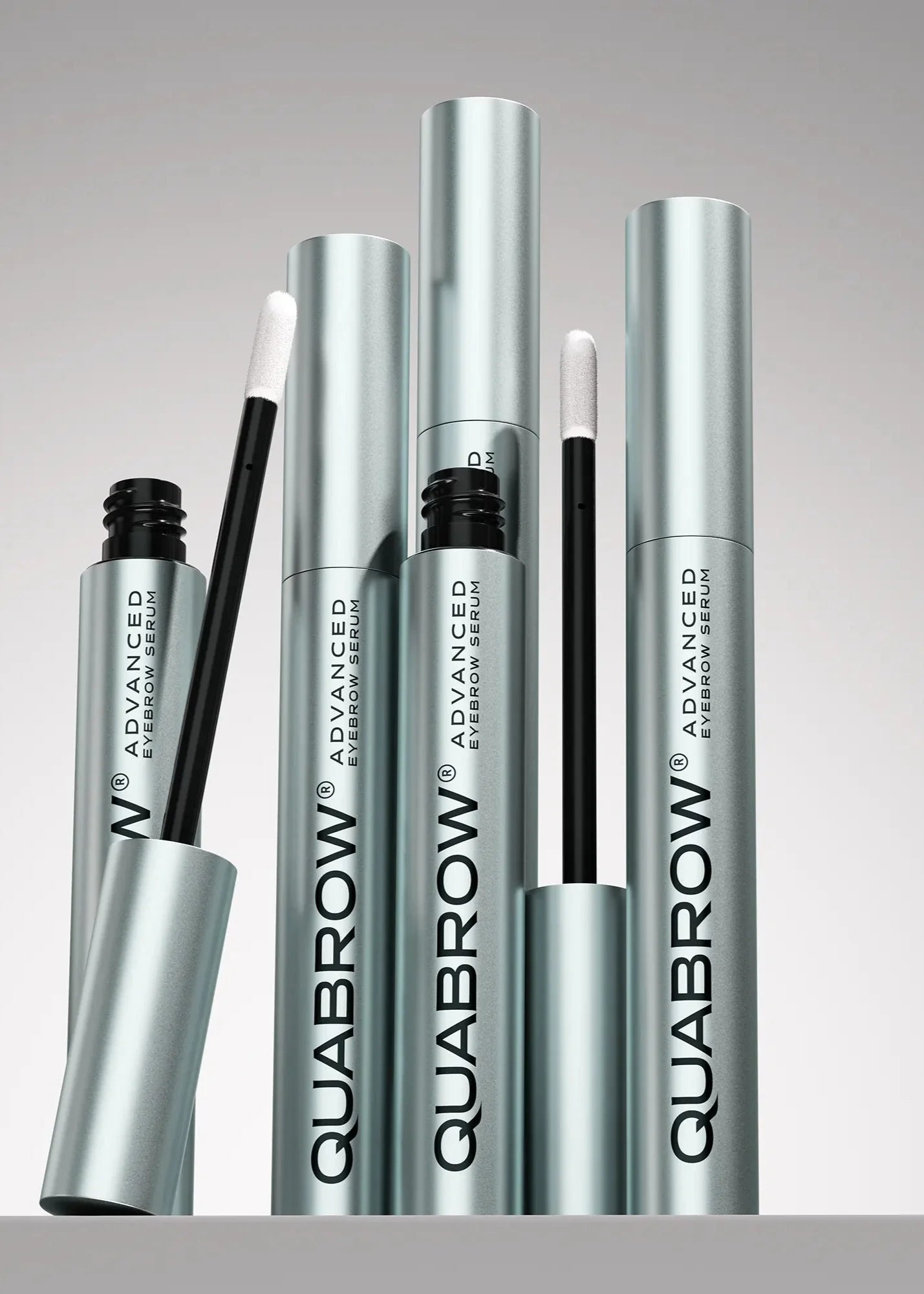 QUABROW Eyebrow Serum Trio Set arranged upright with open applicators on a soft grey background